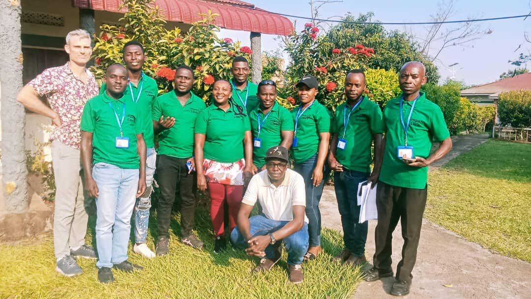 Impact Lines consultants and enumerators in green Impact Lines shirts, standing together outdoors
